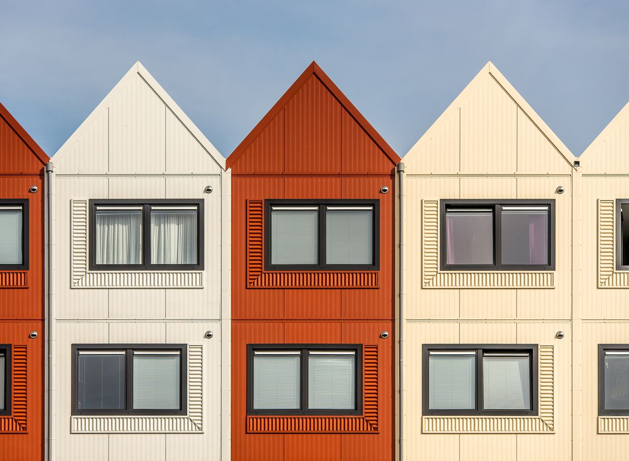 Contemporary row houses with vibrant color palette under a clear sky, showcasing modern architecture.